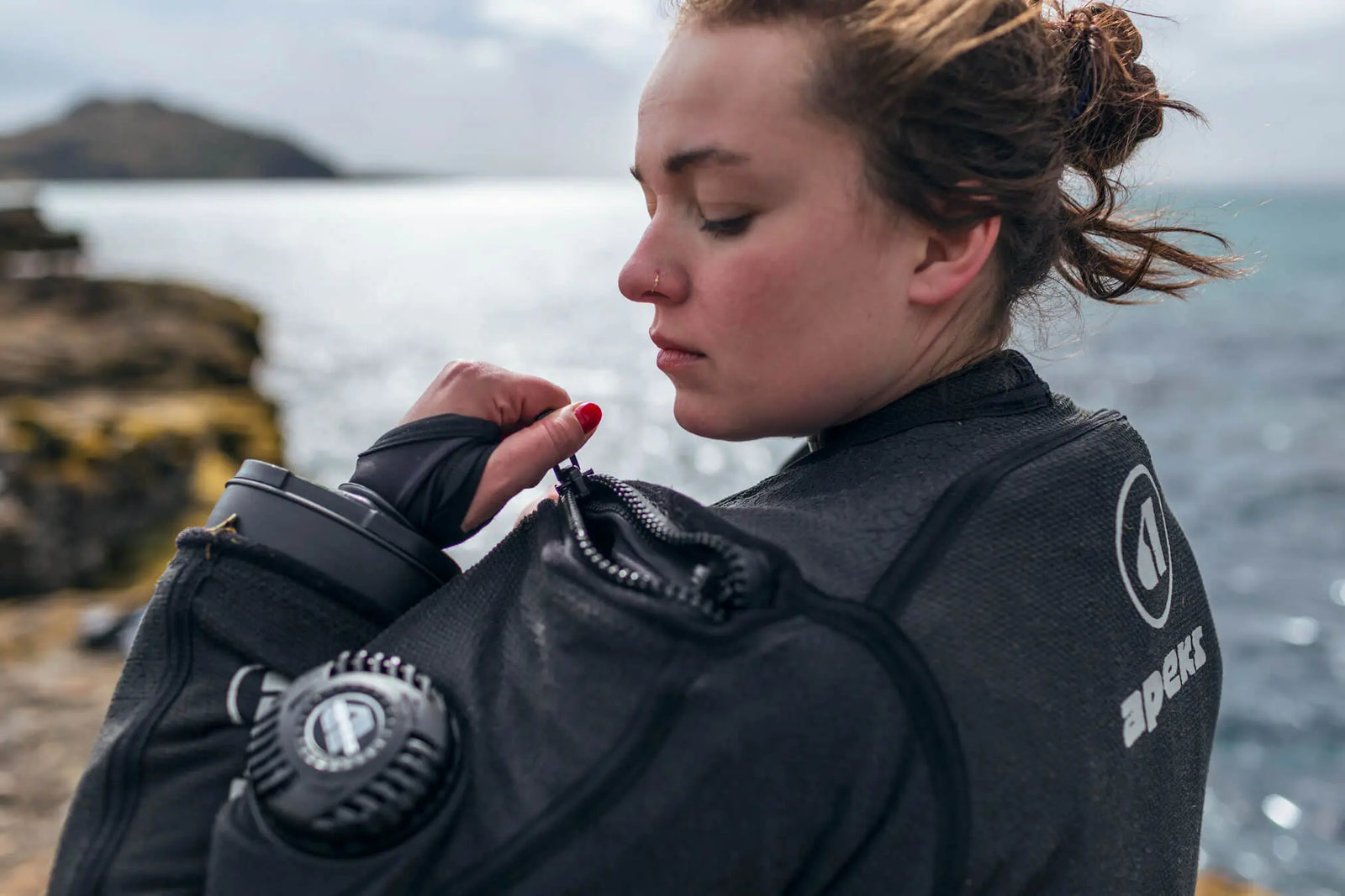 Woman Wearing Apeks drysuit standing by the sea 