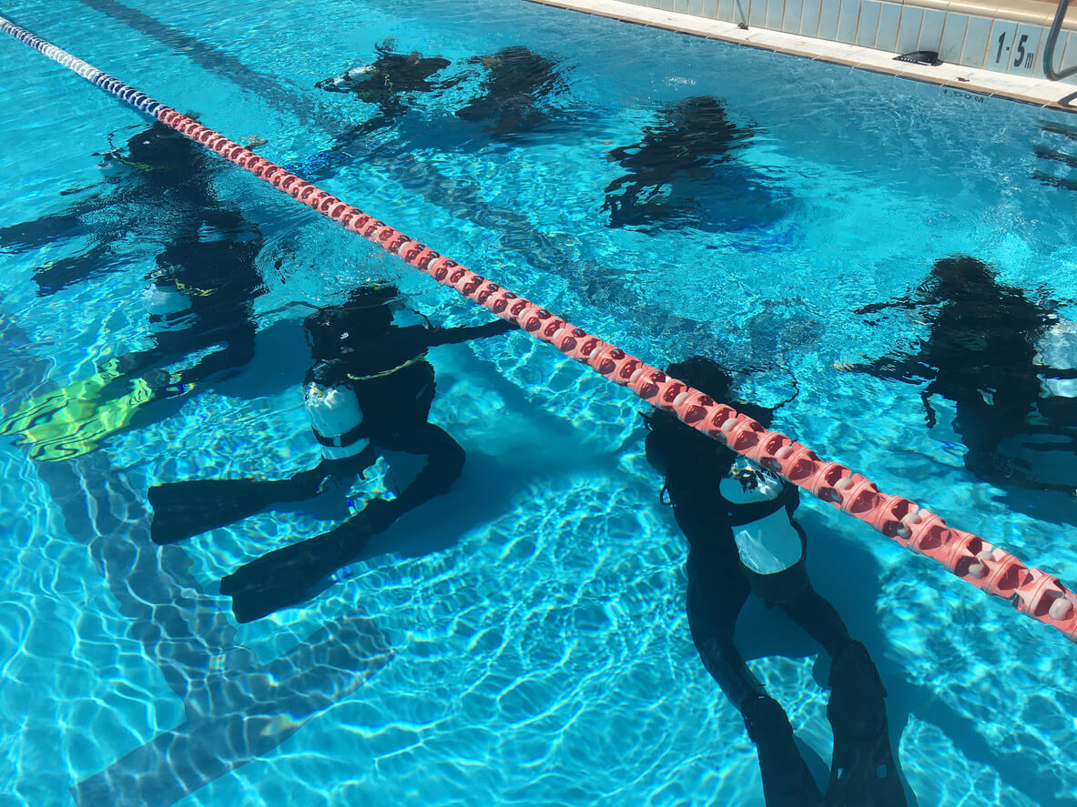 group of scuba divers practising dive skills in a swimming pool