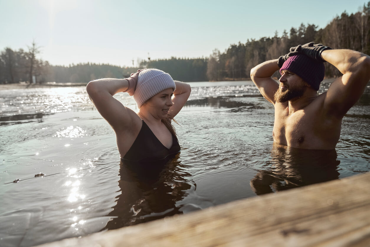 couple stood in cold water lake wearing beanie hats