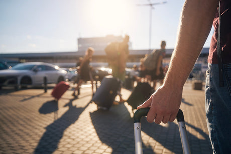 group of people wheeling luggage towards the airport