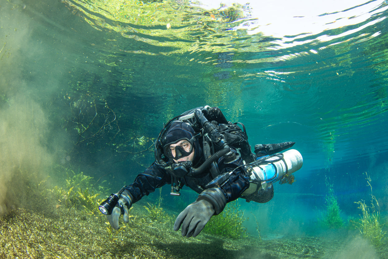 male diver wearing gloves, drysuit, and hood