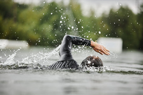 person swimming in open water in a wetsuit
