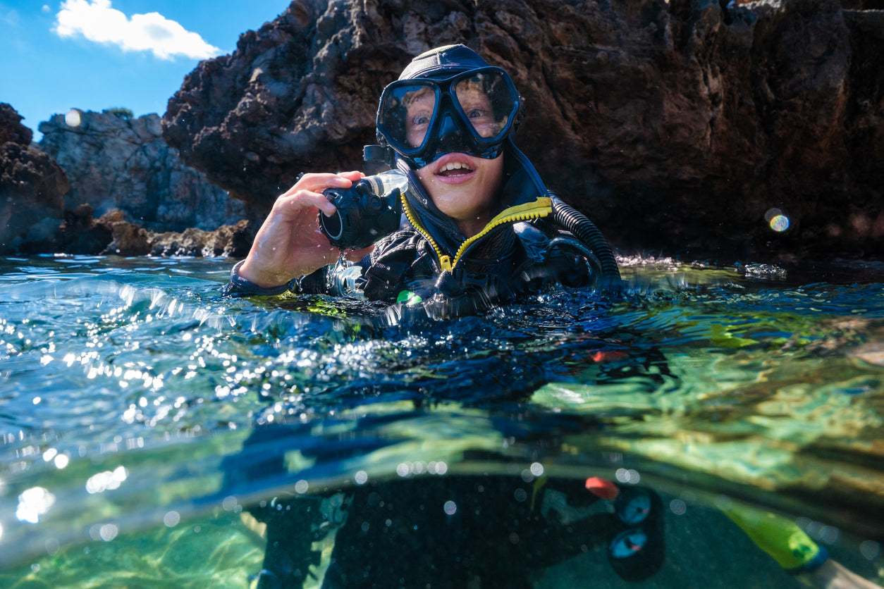 male scuba diver wearing drysuit and mask looking at camera while in the water