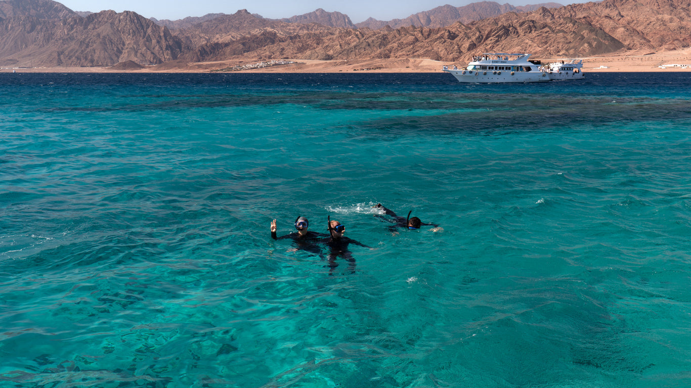 three people snorkelling in sea water