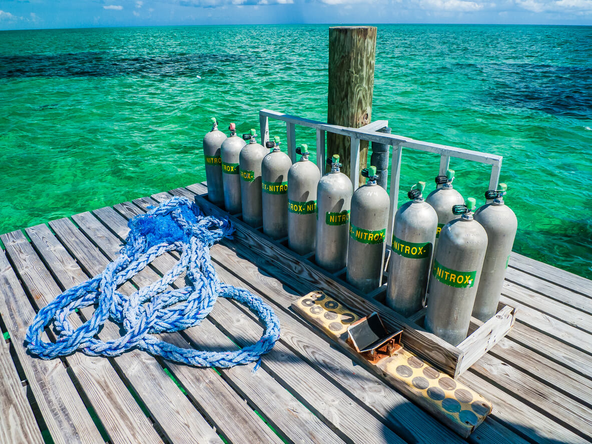 rack of diving cylinders with nitrox labels on a dock next to the ocean